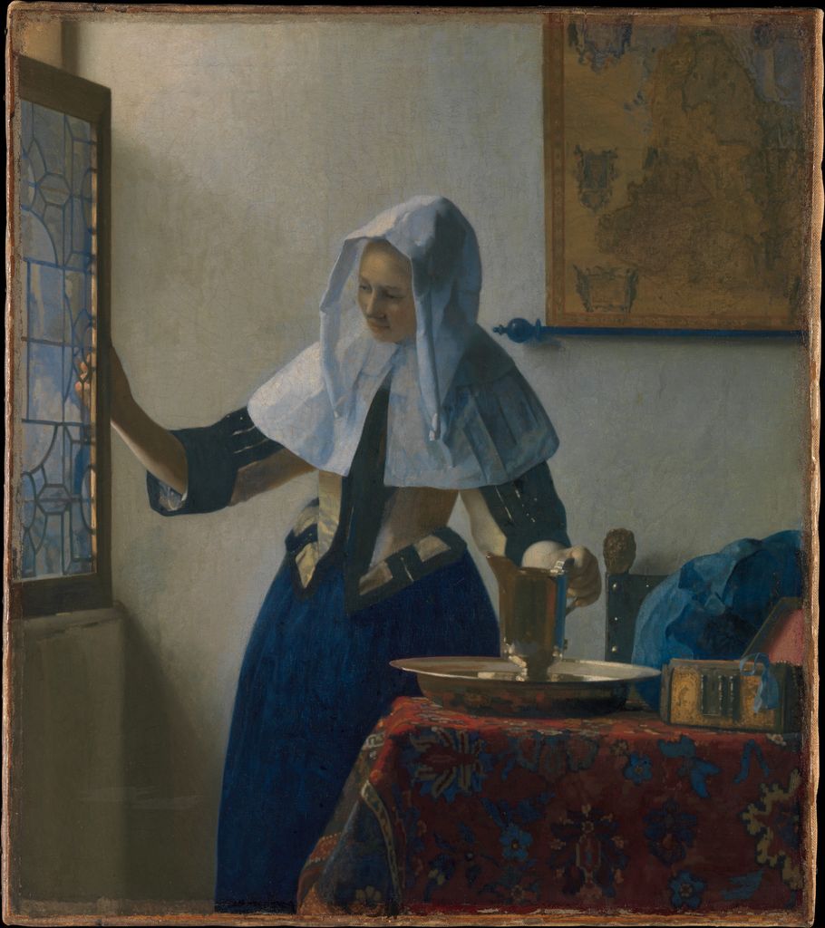 Vermeer's Young Woman with a Water Pitcher stands beside an open window and a table covered with a patterned cloth in a softly lit room.