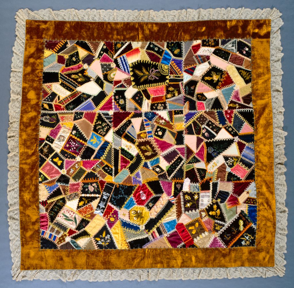 Louisa Joiner's square crazy quilt joins many differently shaped and coloured silk and velvet patches with varied embroidery inside gold and lace borders.