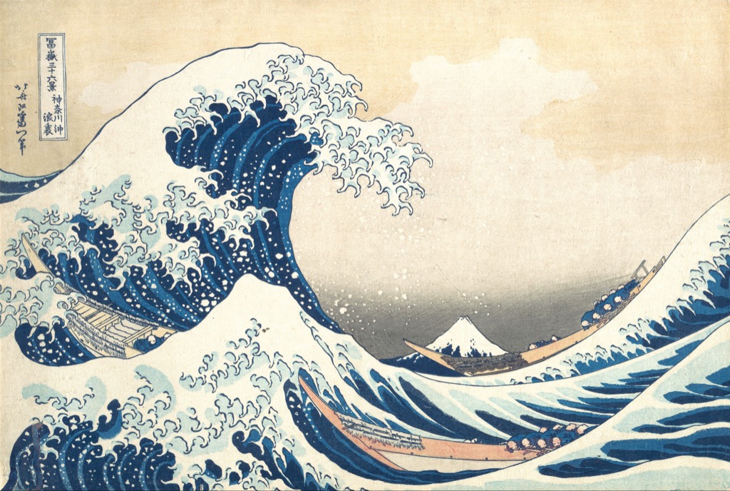 Hokusai colour woodblock print of a towering blue wave above boats with Mount Fuji beyond