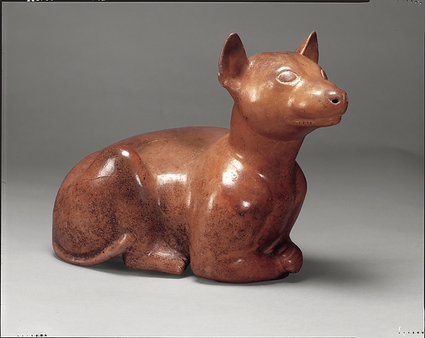 Hollow Colima ceramic dog with upright ears, rounded volumes and polished reddish slip.