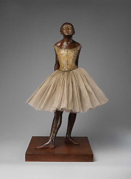 Degas standing dancer in partially tinted bronze wearing a fabric tutu and hair ribbon.