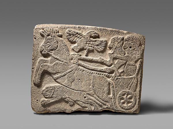 Basalt wall relief showing a mounted hunter drawing a bow towards a lion.