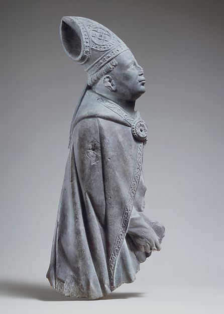 Limestone relief of a bishop holding a crozier beneath a pointed canopy.