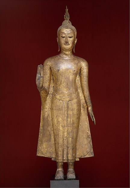 Gilt-bronze Thai Buddha standing with both hands raised.