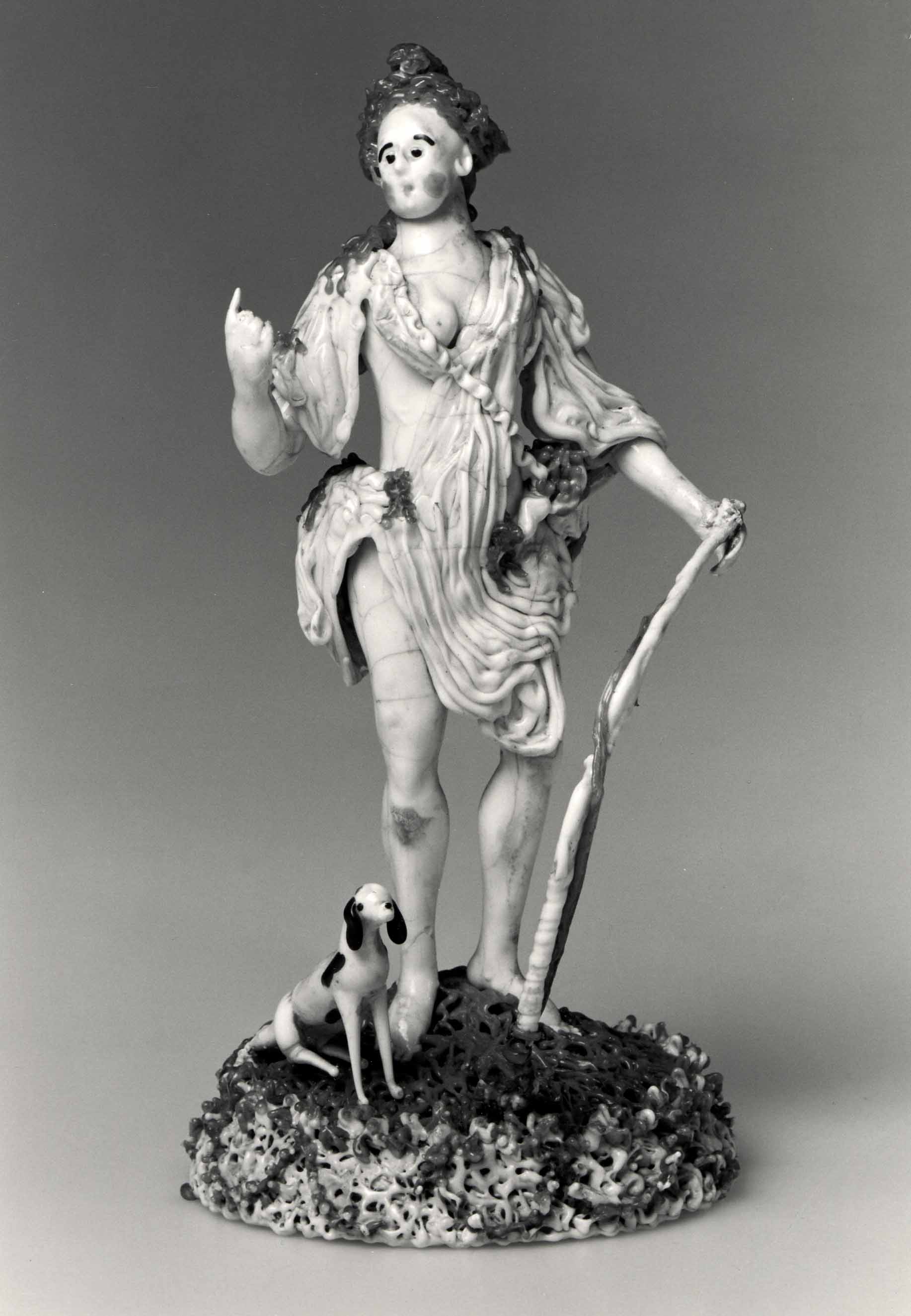 Small lampworked-glass Diana standing with a bow and dog on an open textured base, incorporating copper and iron wire.